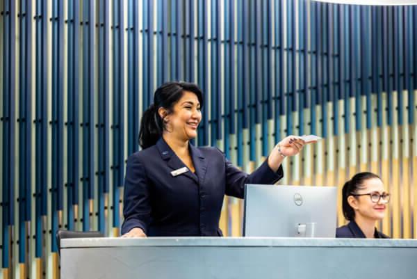 Female front of house reception staff handing an access card to a visitor